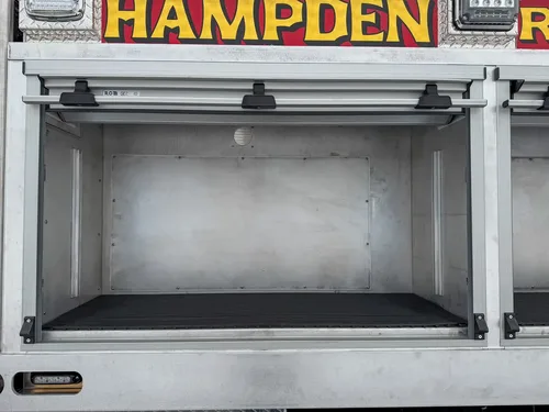 Open side compartment with aluminum shelves and rubber floor mat.